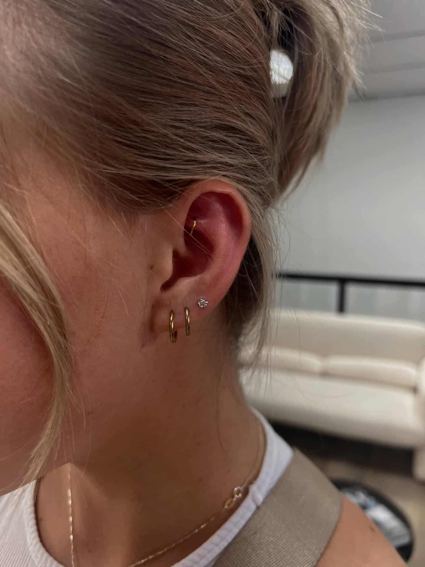 Curated ear stack with gold lobe hoops and cartilage studs pierced at Aurilus in American Fork, Utah