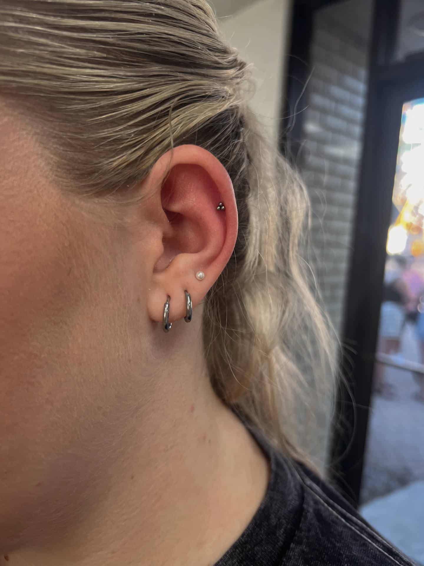 Multiple lobe piercings finished with gold hoops and small studs