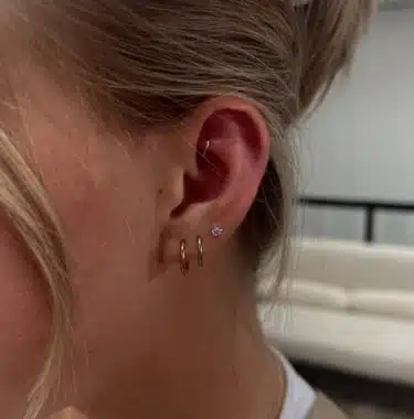 Curated ear with stacked lobe piercings and a cartilage stud