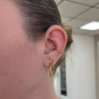 Healed ear piercings styled with implant-grade gold jewelry